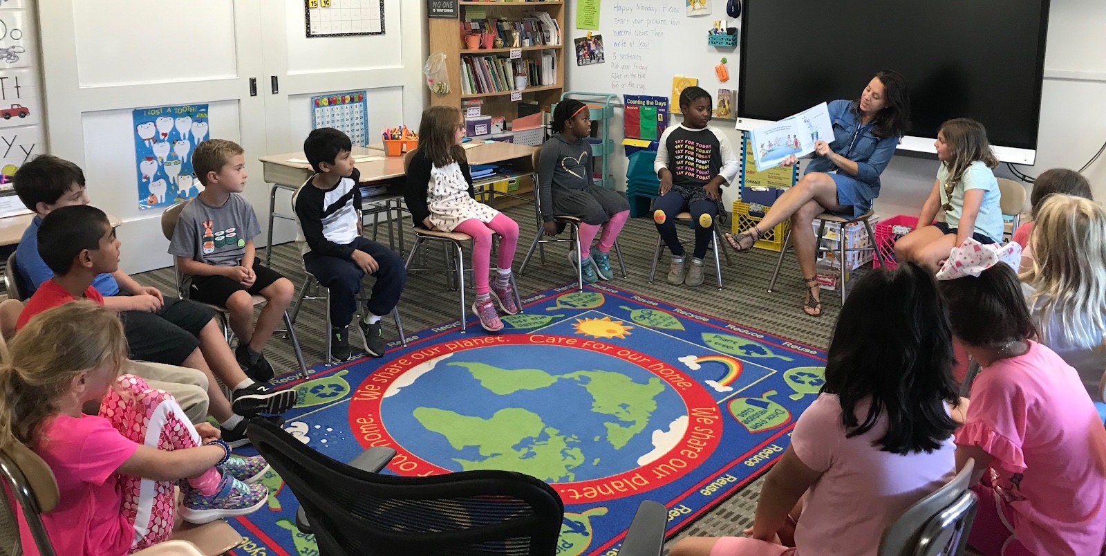 An Open Circle session where the teacher and students are seated around a rug with a map of the globe in the center