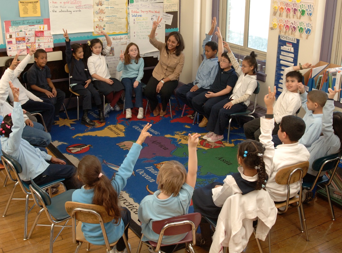 The students and teachers raise their hands in an Open Circle session
